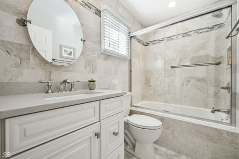 Primary bathroom at 12344 St Armands Circle, Carmel, IN — Elegant primary bath with marble tile and glass shower.