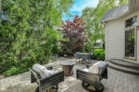 Outdoor living area at 12344 St Armands Circle, Carmel, IN — Spacious paver patio with fire pit and mature landscaping.