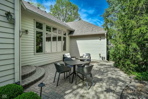 Backyard at 12344 St Armands Circle, Carmel, IN — Spacious paver patio with mature privacy hedges and seating.