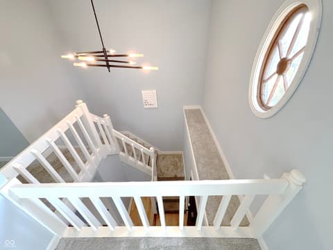 Hallway at 9728 Revere Way, Indianapolis, IN — Bright stairwell with modern lighting and circular window.