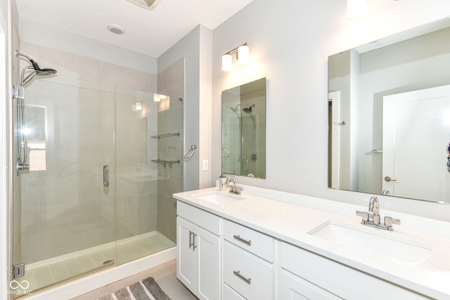 Luxurious primary bath with dual vanity and frameless shower.