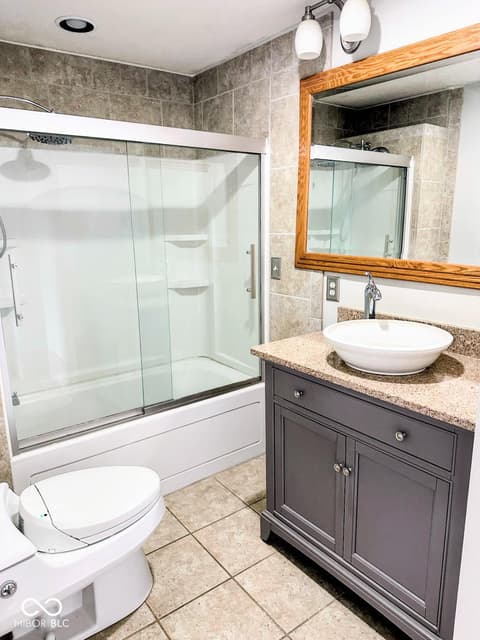 Primary bathroom at 310 2nd Street NE, Carmel, IN — Updated primary bath with glass shower and granite surfaces.