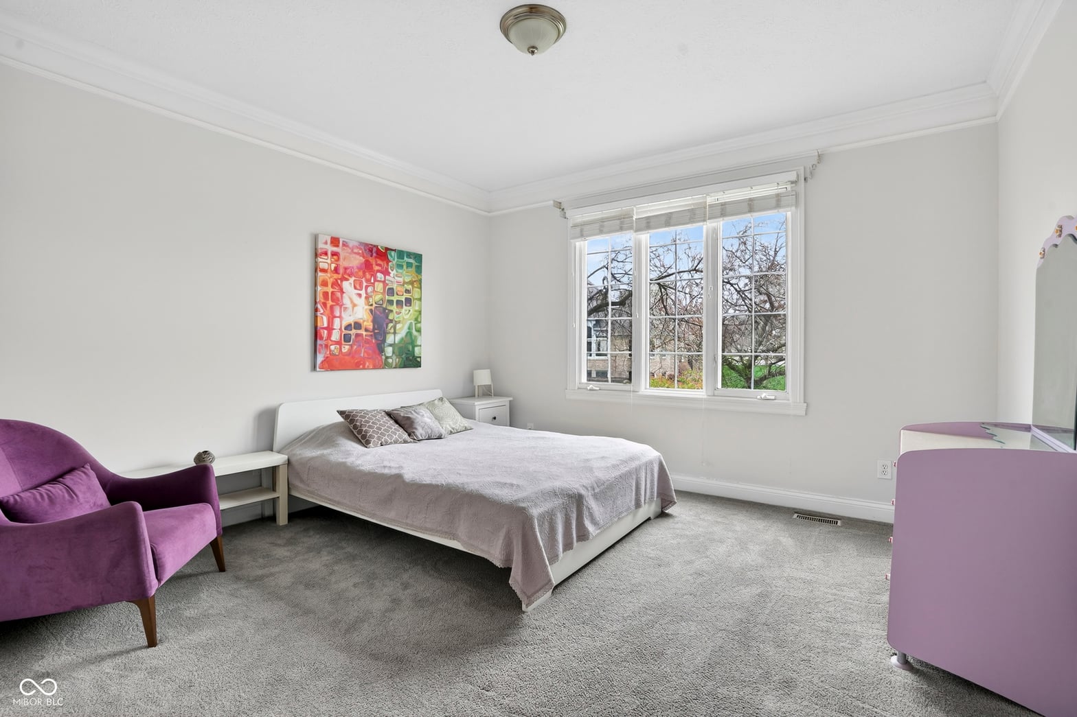 Bright primary bedroom with expansive windows and modern furnishings.
