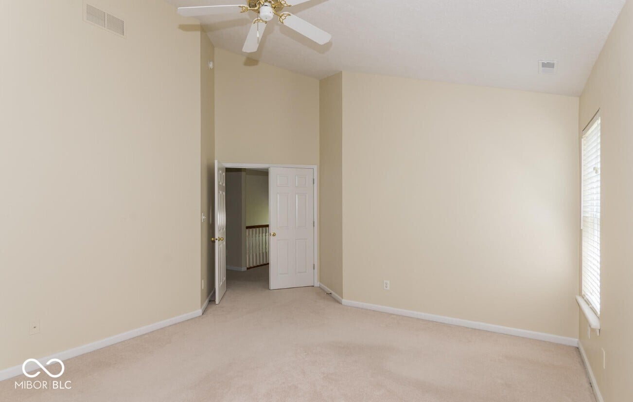 Spacious primary bedroom with high ceilings and natural light.