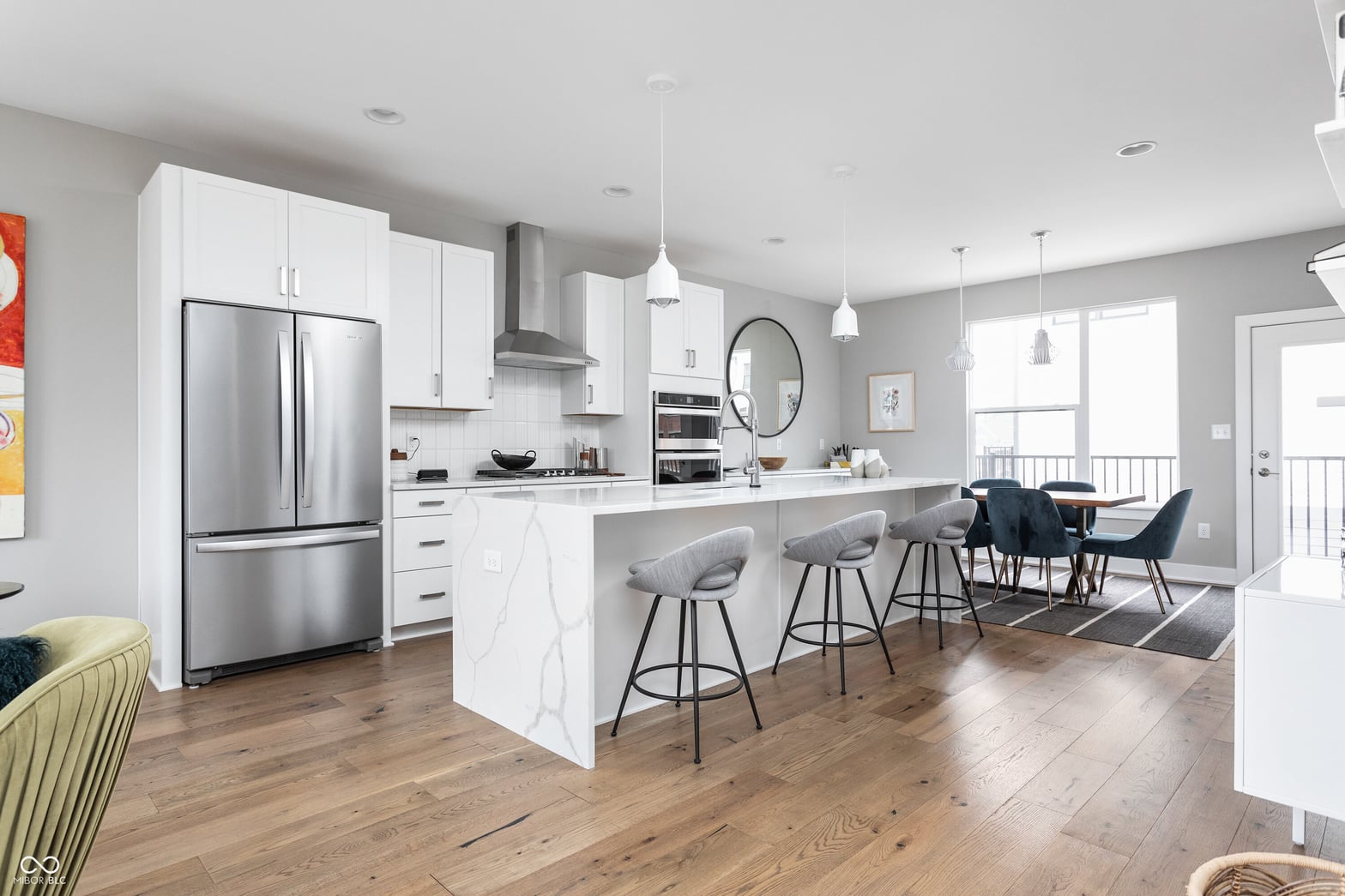 Modern white kitchen with marble island and stainless appliances.