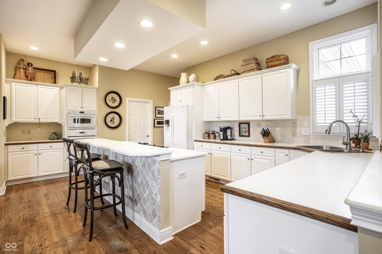 Bright, spacious kitchen with white cabinetry and island seating.