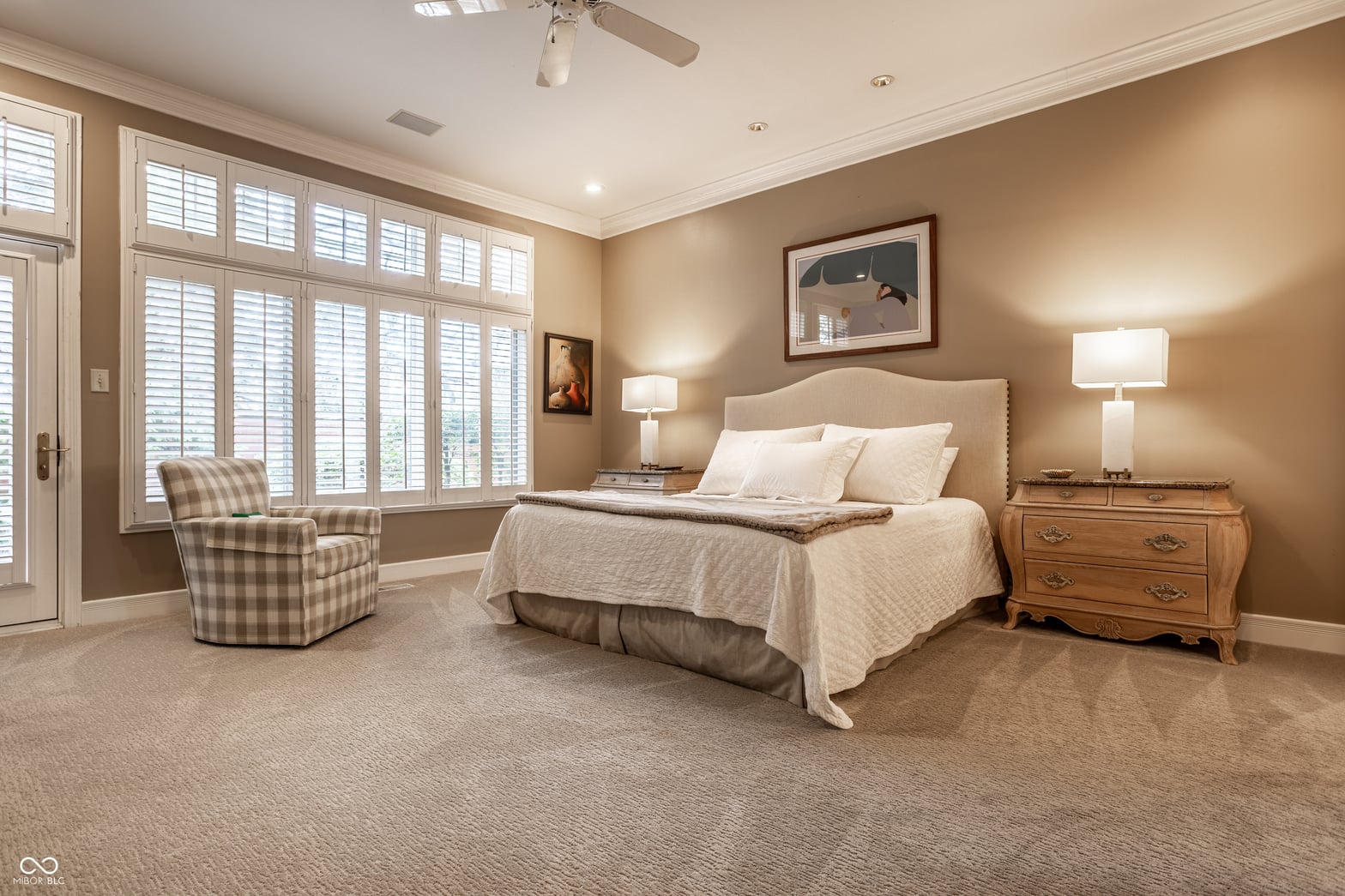 Spacious primary suite with plantation shutters and sitting area.