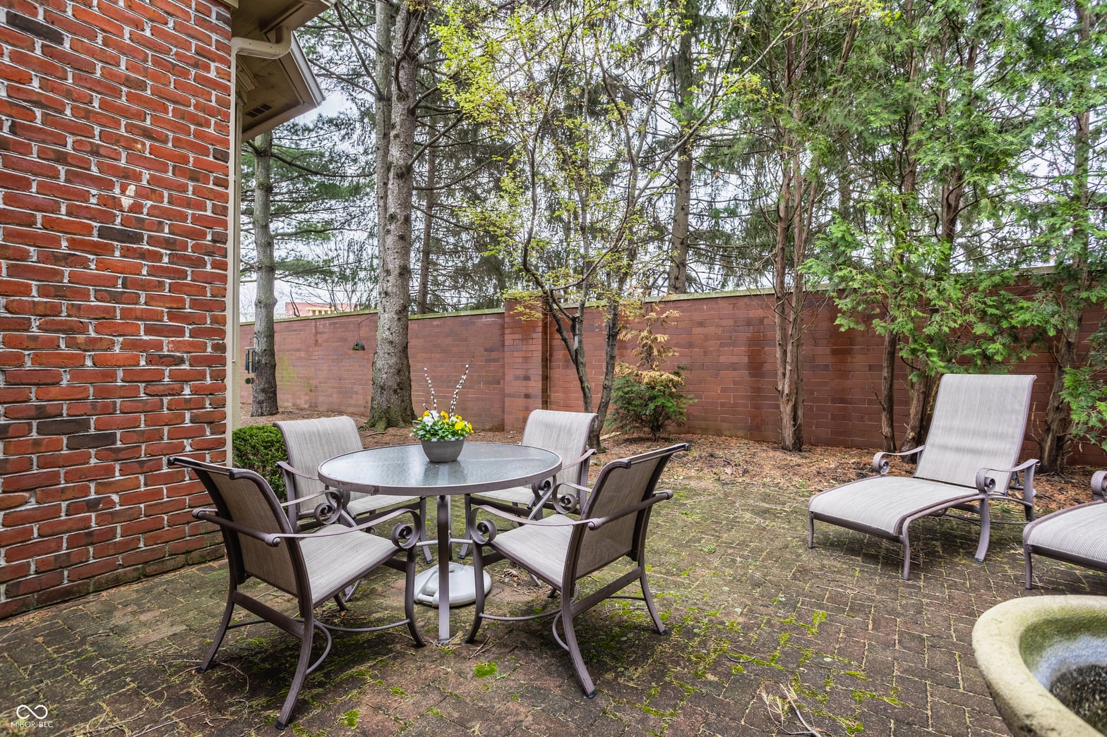Private brick patio with mature trees and seating areas.
