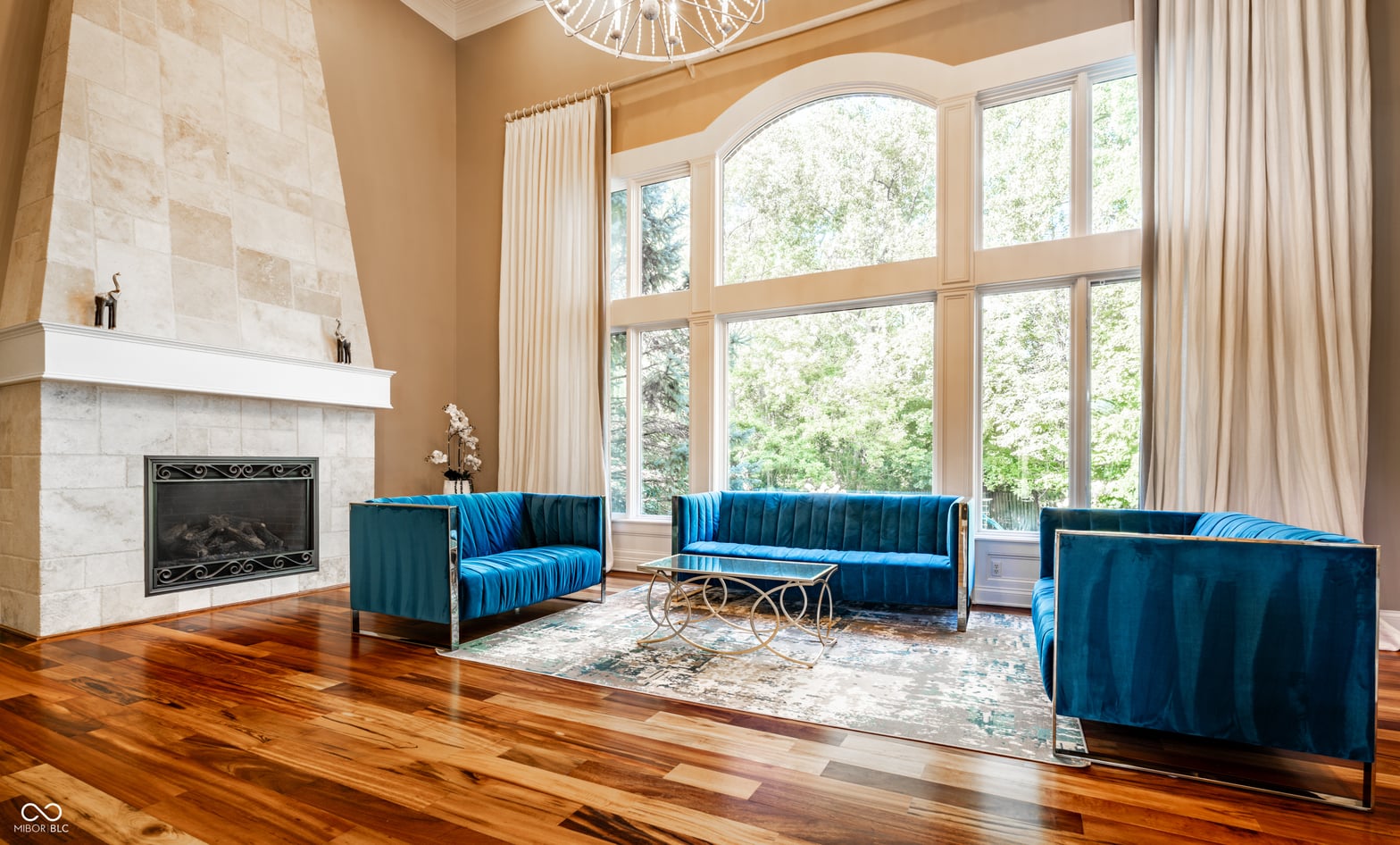 Luxurious living room with marble fireplace and soaring windows.