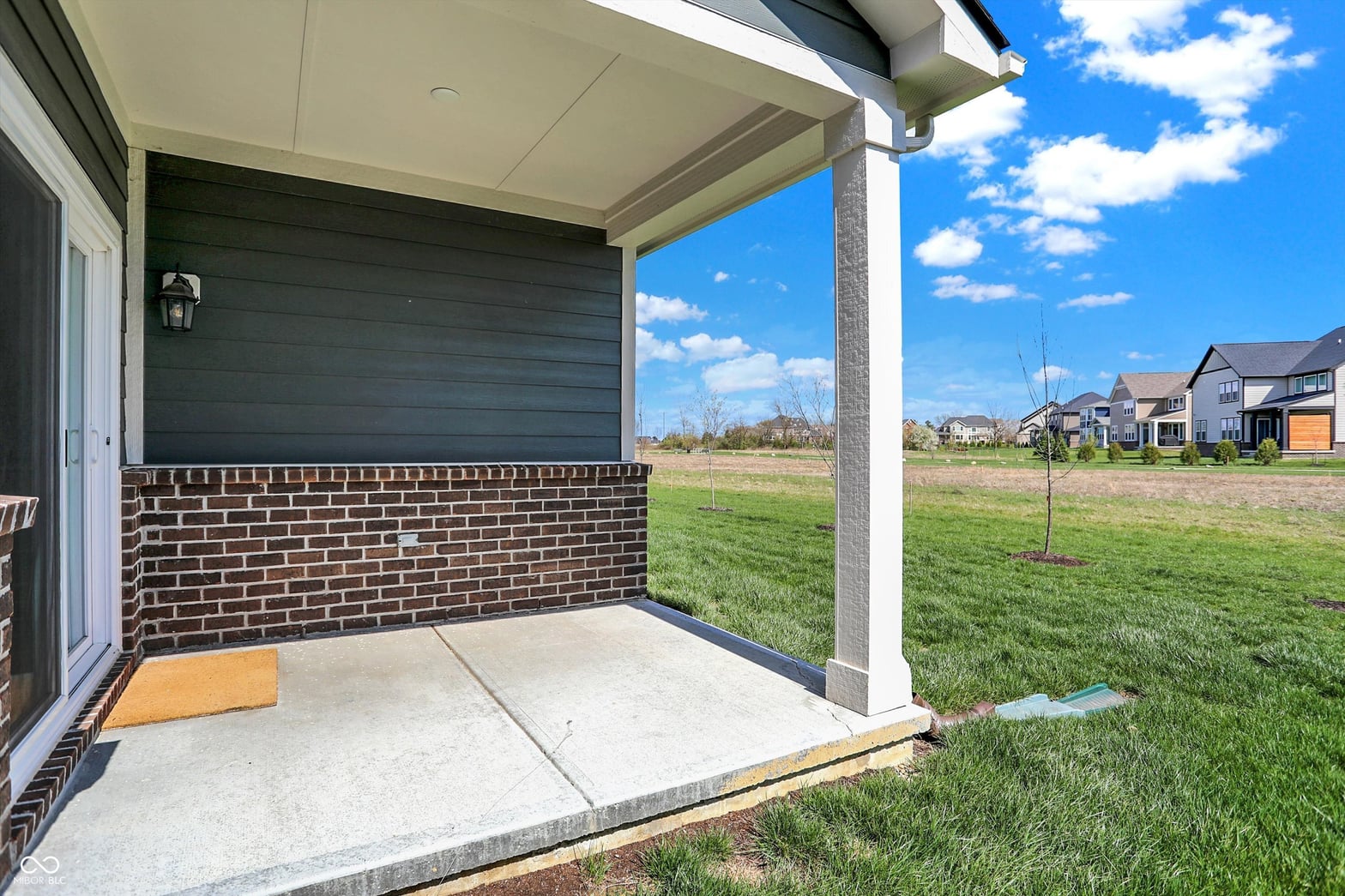 Spacious covered patio with concrete pad and open yard.