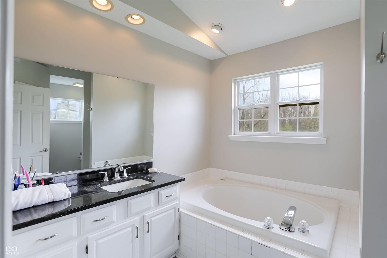 Spacious primary bath with soaking tub and granite counters.