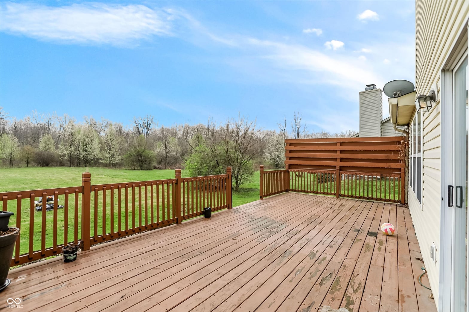 Spacious wooden deck overlooking open green yard.
