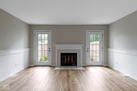 Living room at 6047 Southbay Drive, Indianapolis, IN — Bright living room with fireplace and dual french doors.