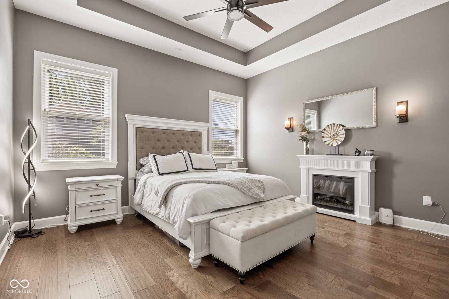 Luxurious primary suite with fireplace and tray ceiling.