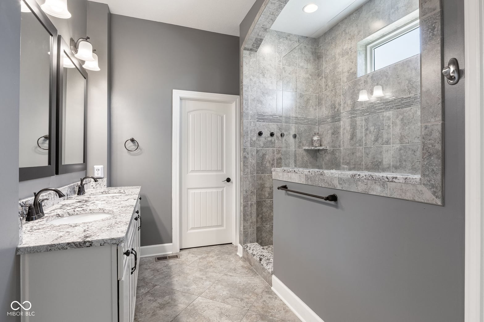 Luxurious primary bath with walk-in shower and granite vanity.