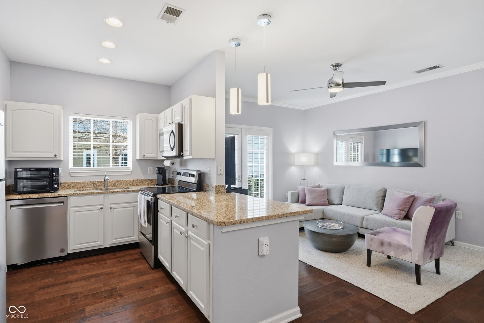Modern kitchen with granite island opens to bright living space.