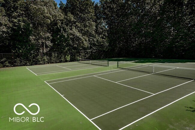 Professional-grade tennis courts with mature tree backdrop.