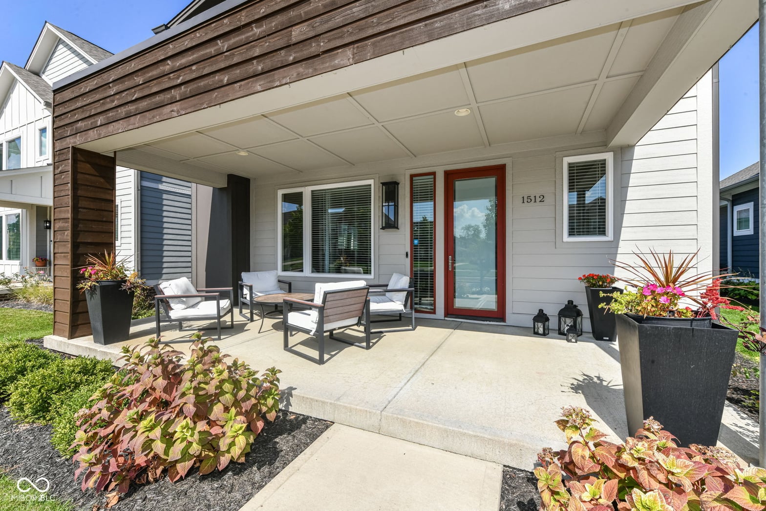 Modern covered patio with seating and manicured landscaping.