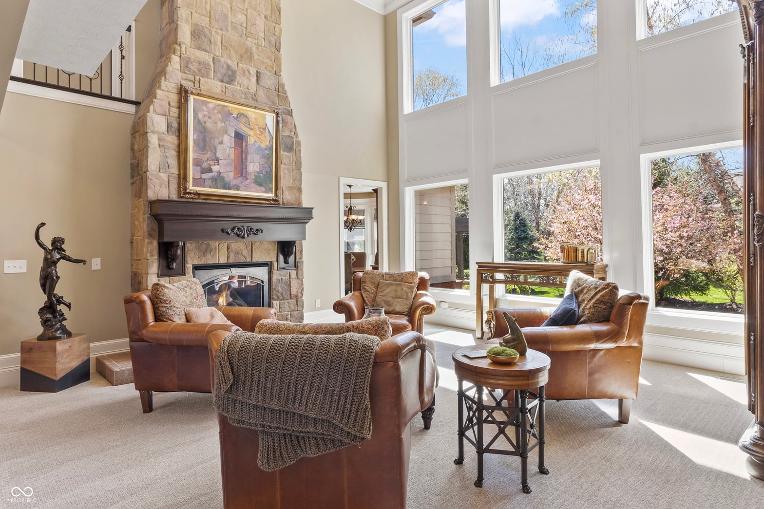 Stunning two-story living room with stone fireplace and abundant natural light.