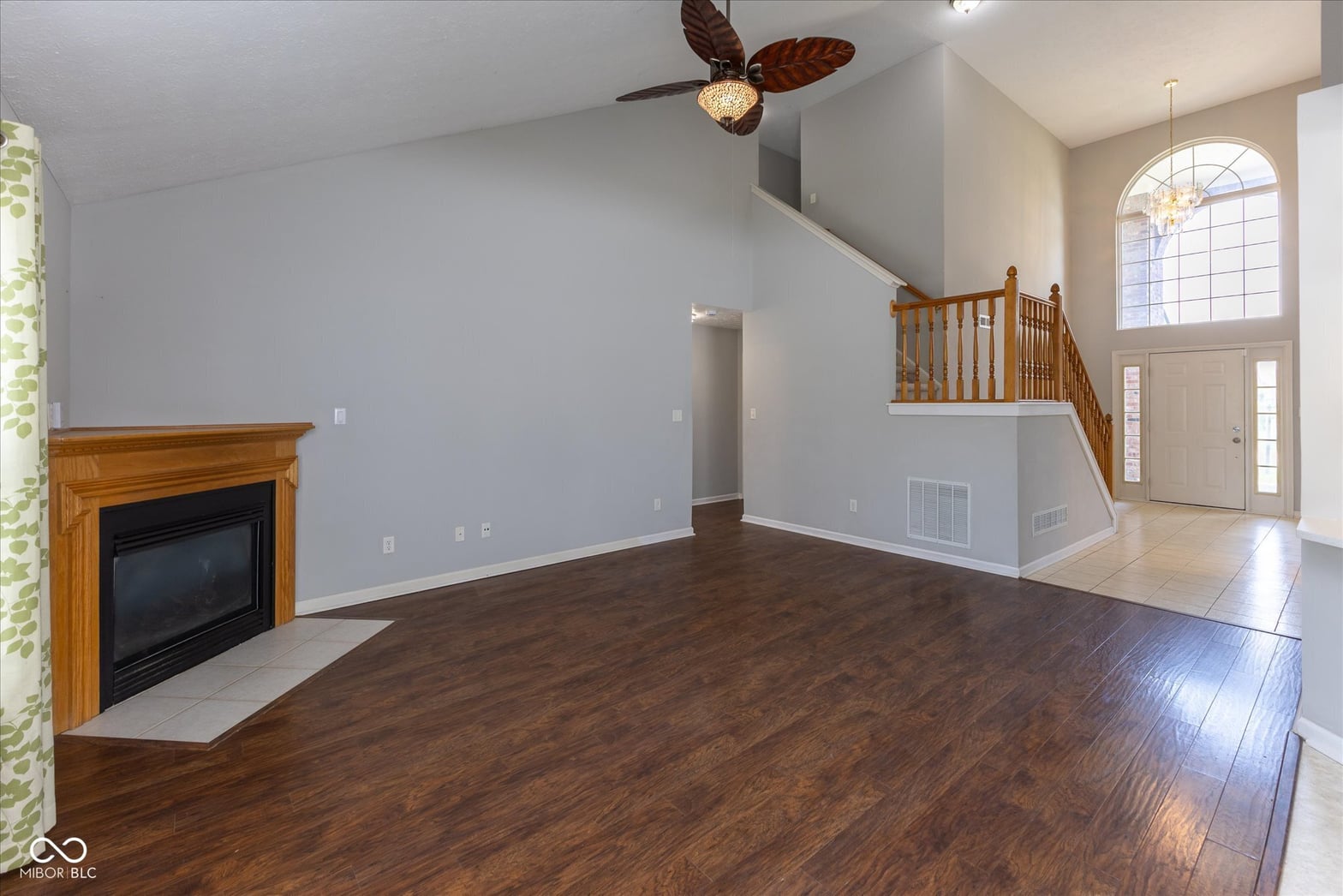 Bright two-story living room with fireplace and elegant staircase.