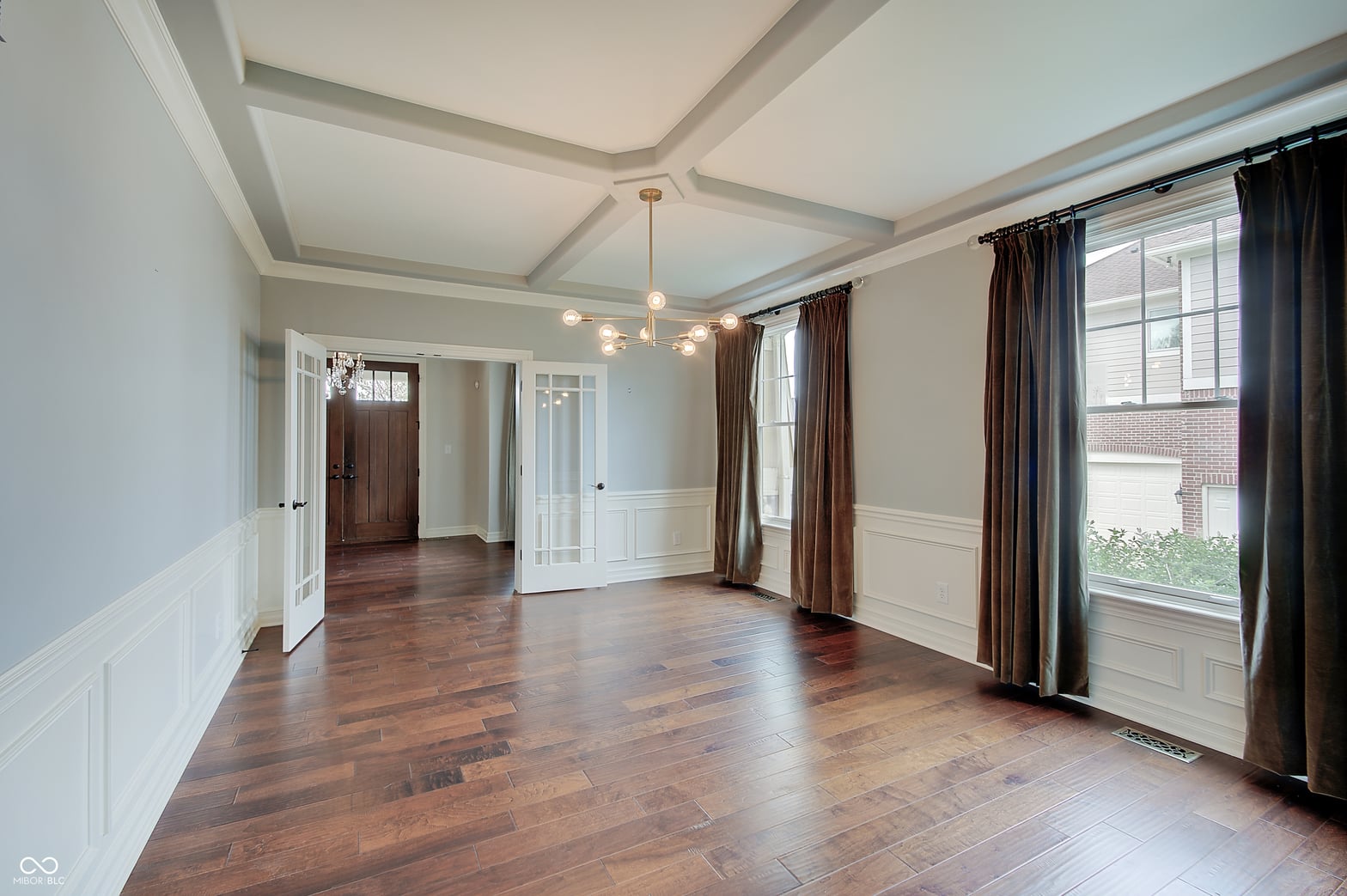 Elegant family room with coffered ceiling and hardwood floors.