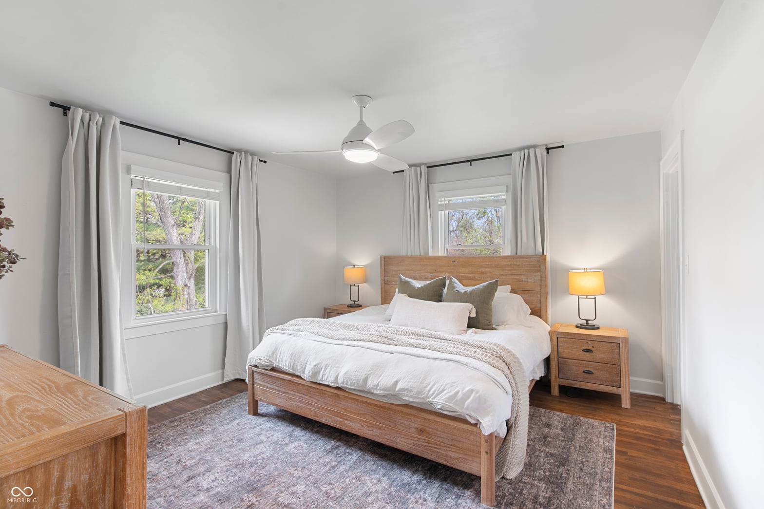 Bright primary bedroom with hardwood floors and abundant windows.