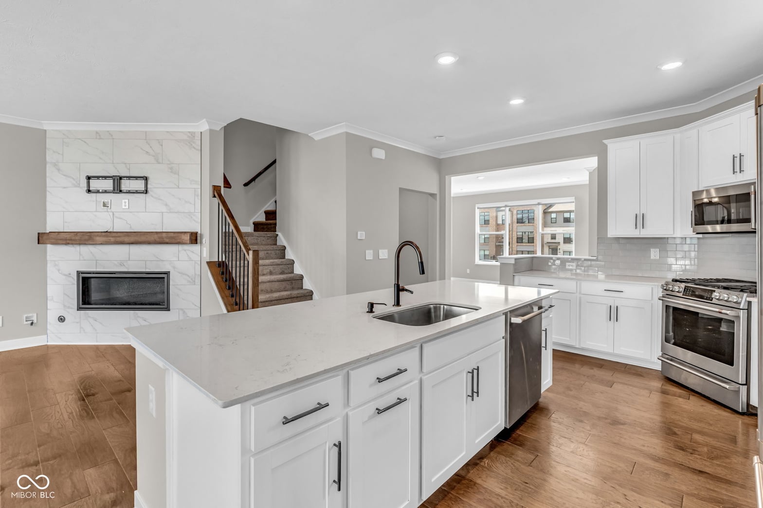 Modern white kitchen with quartz island and stainless steel.