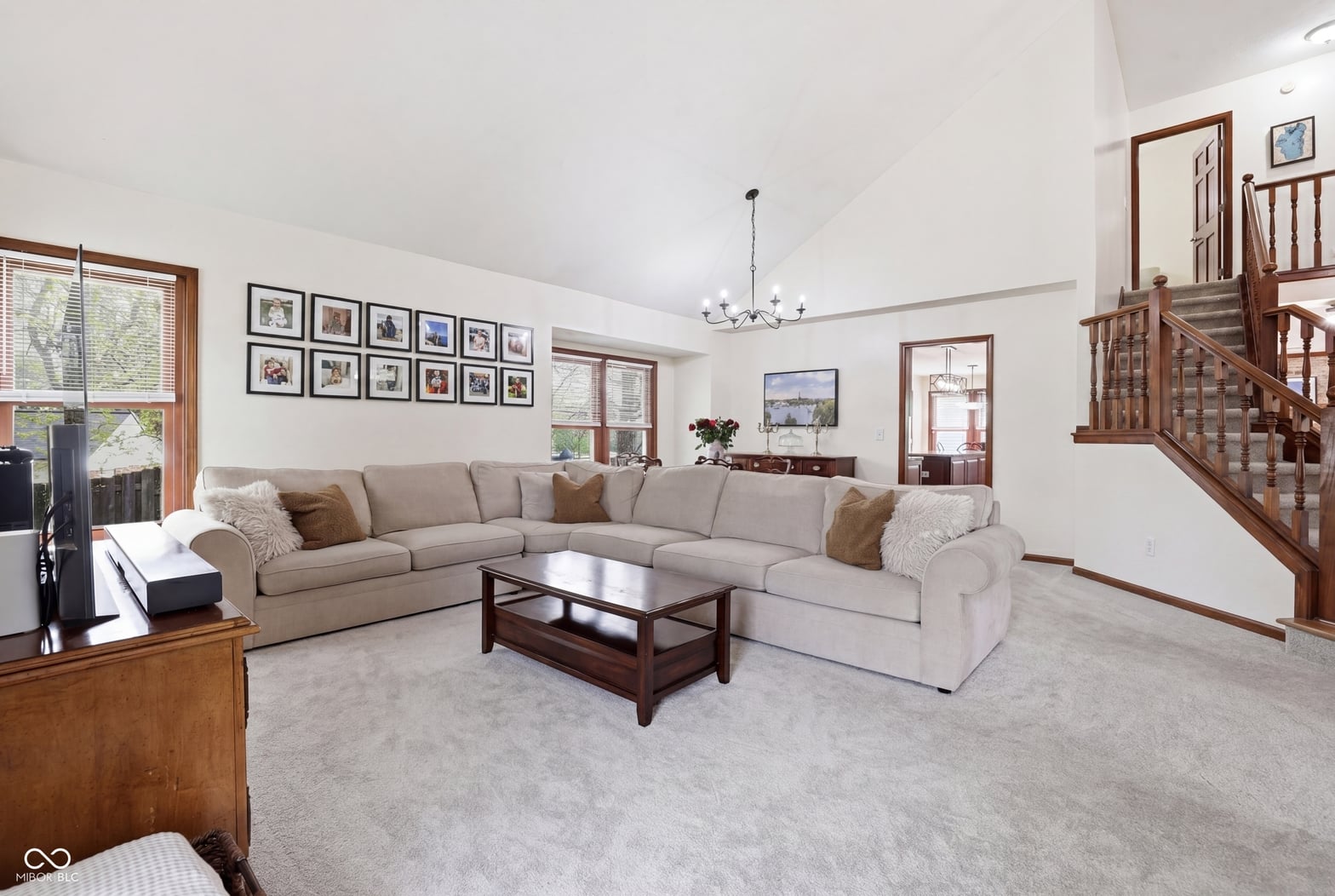 Spacious living room with vaulted ceilings and wood staircase.