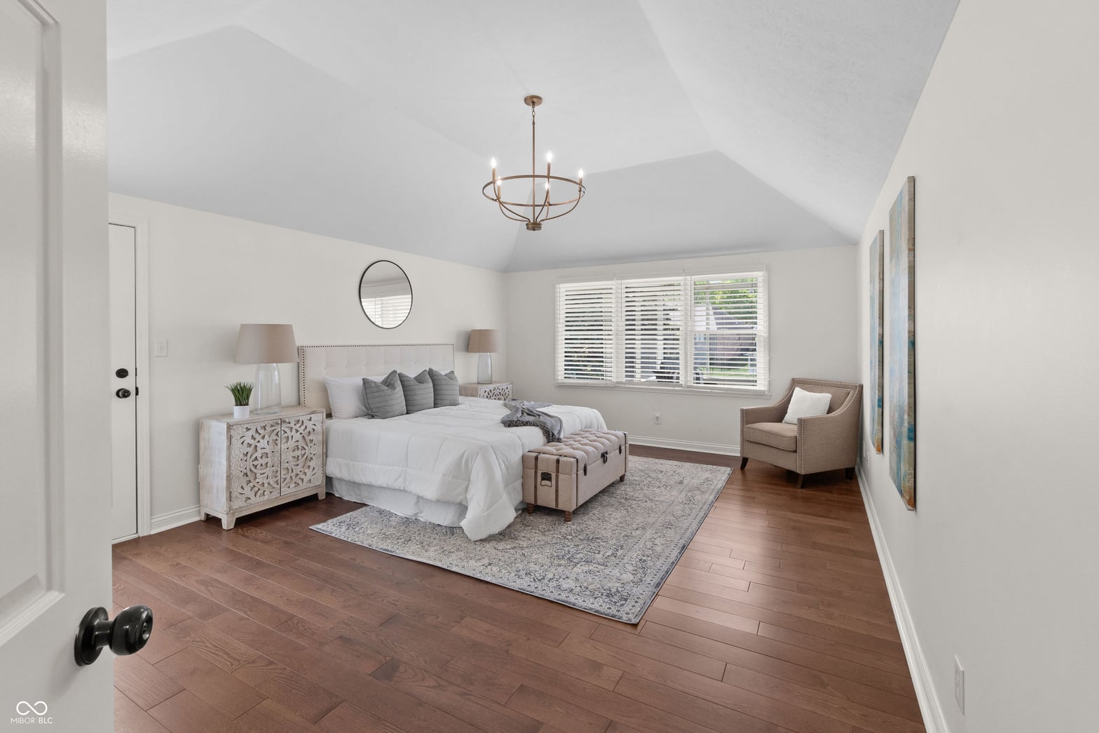 Spacious primary suite with vaulted ceilings and hardwood floors.