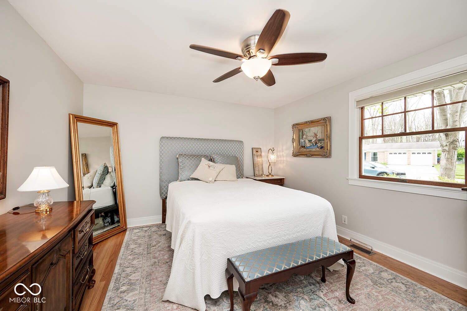 Bright primary bedroom with hardwood floors and windows.