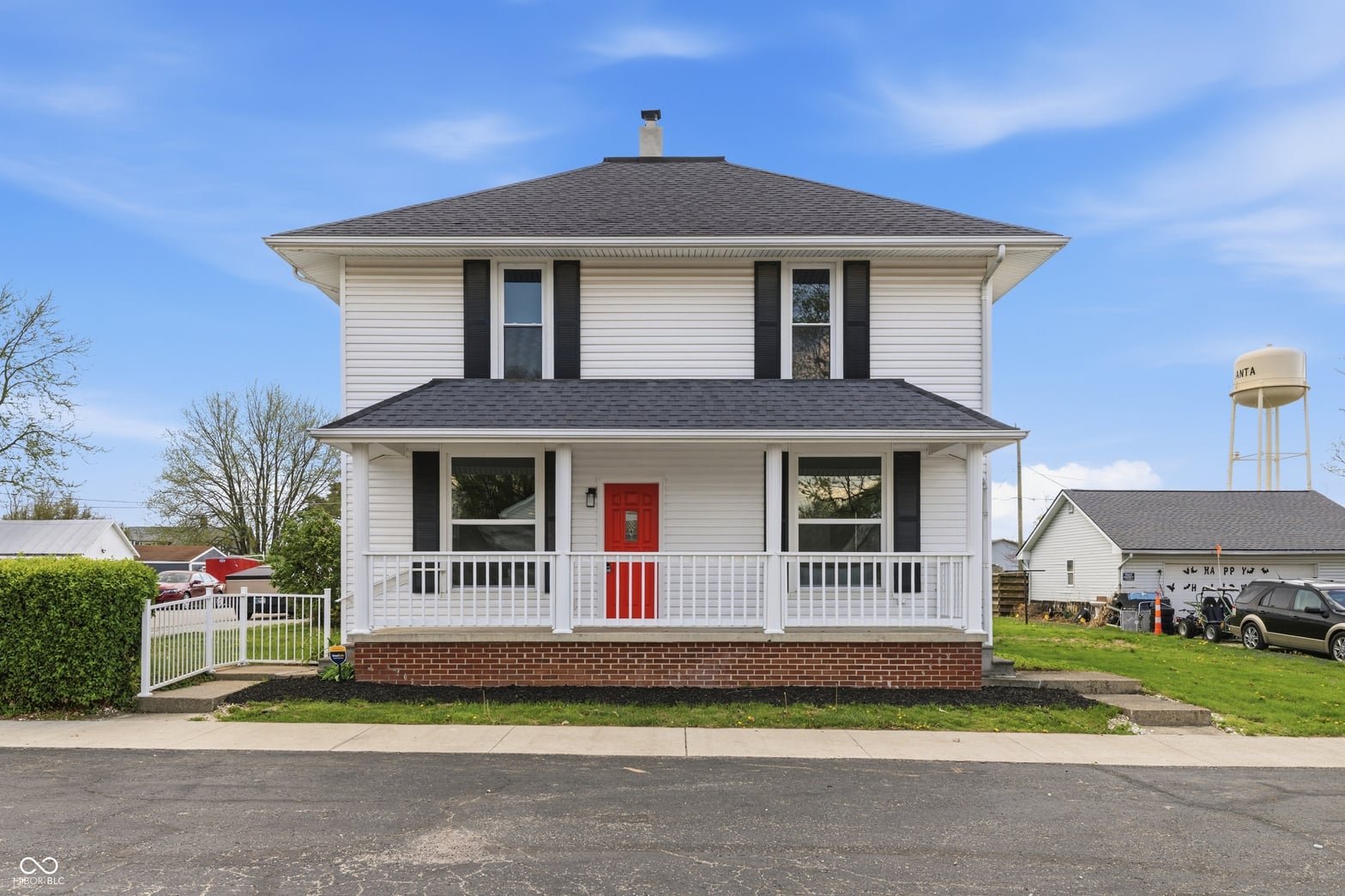 Front exterior at 350 S Broadway Street, Atlanta, IN — Classic farmhouse with updated front porch and red door.