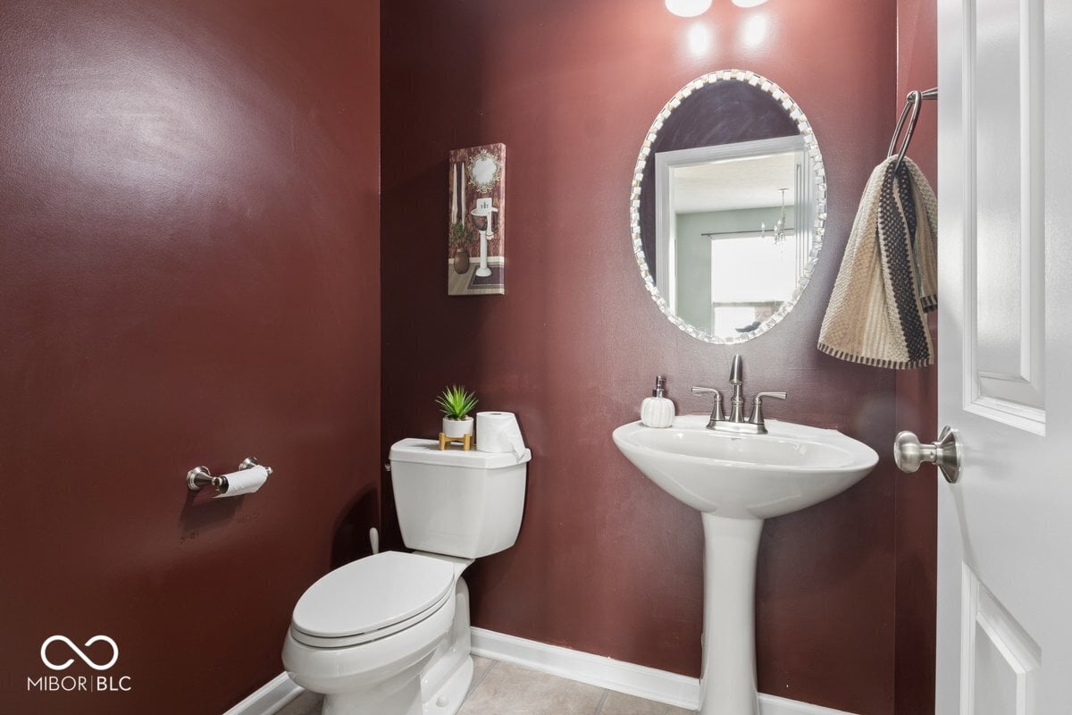 Stylish burgundy bath with modern pedestal sink and lighting.