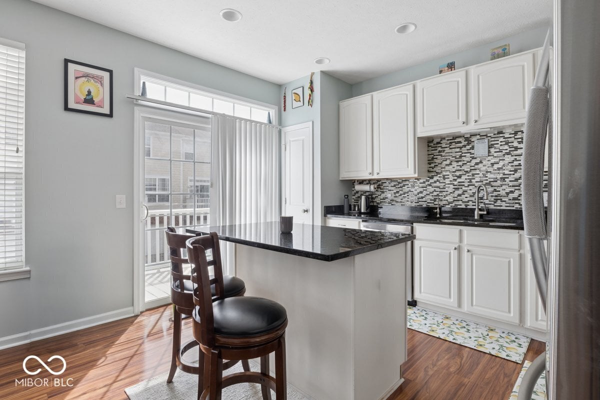 Bright renovated kitchen with granite island and deck access.