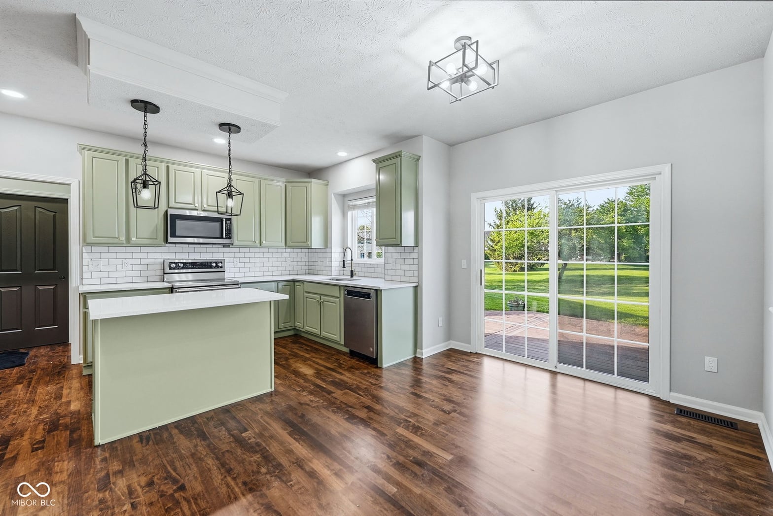 Bright renovated kitchen with sage cabinets and patio access.