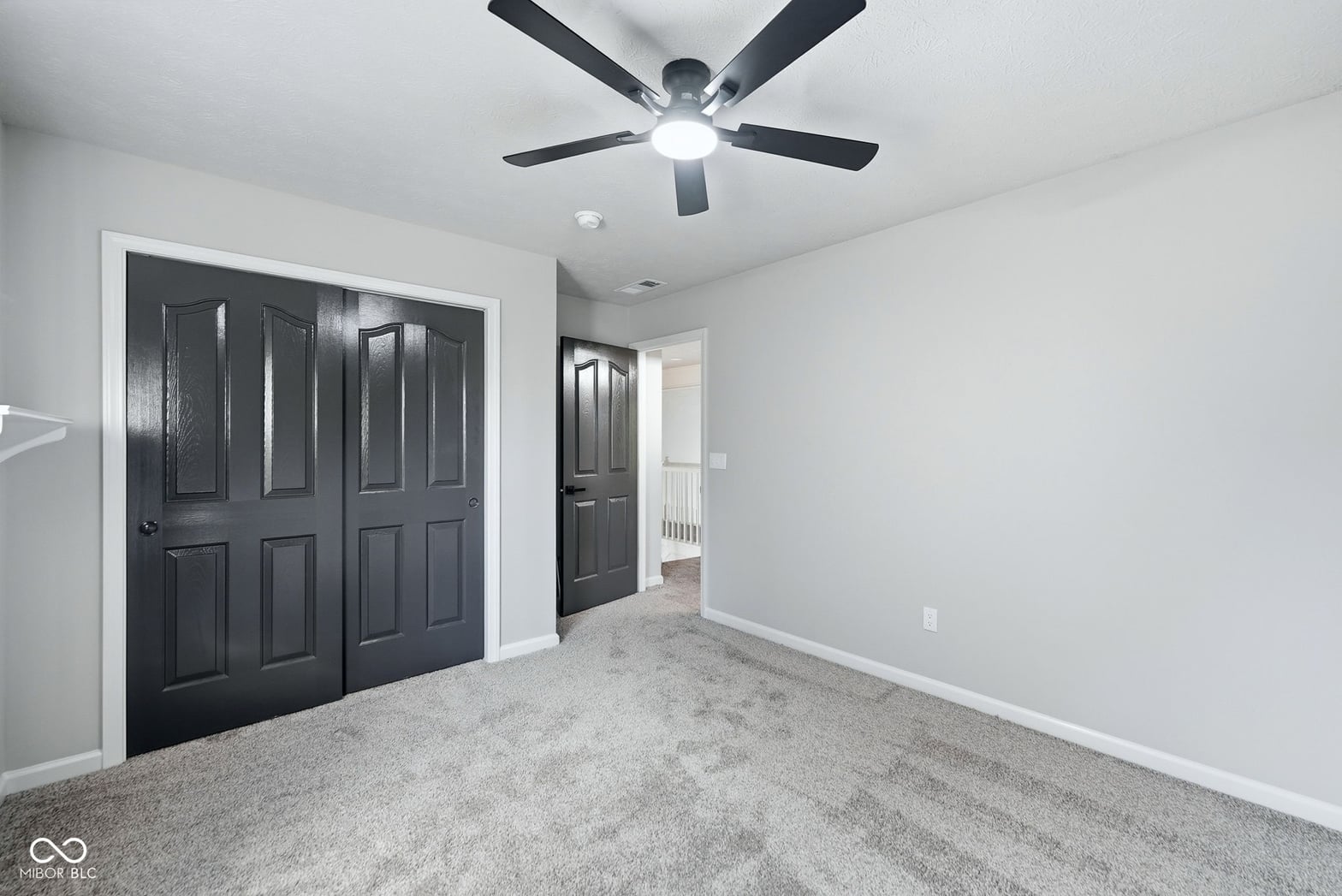 Spacious primary bedroom with modern ceiling fan and closet.