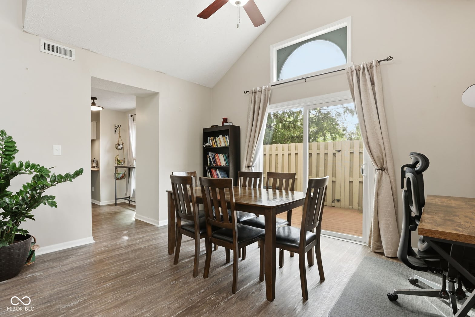 Bright dining area with vaulted ceilings and deck access.