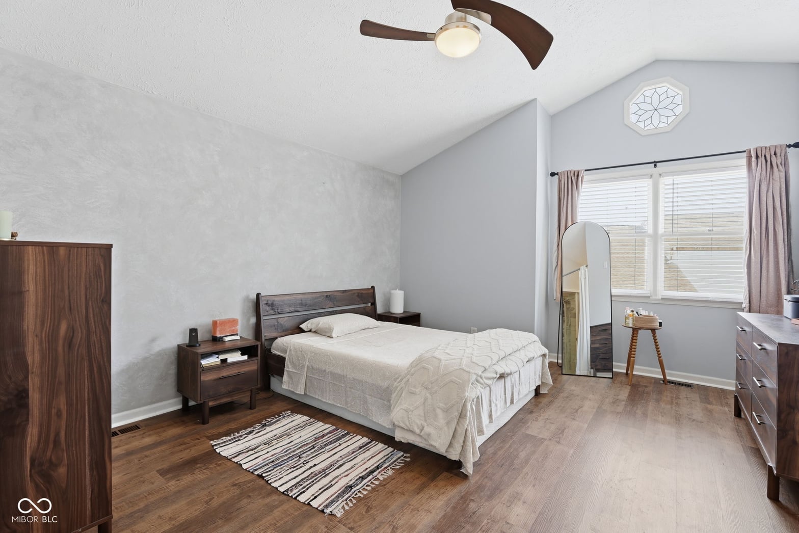 Bright primary bedroom with hardwood floors and ample windows.