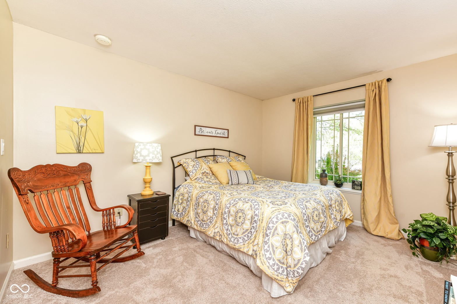 Bright primary bedroom with large windows and elegant furnishings.