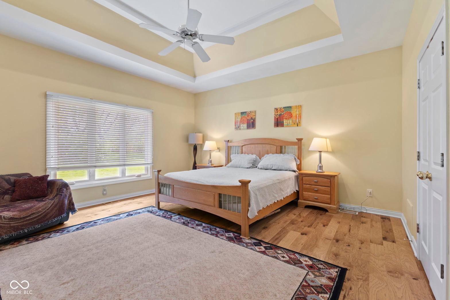 Spacious primary bedroom with tray ceiling and sitting area.