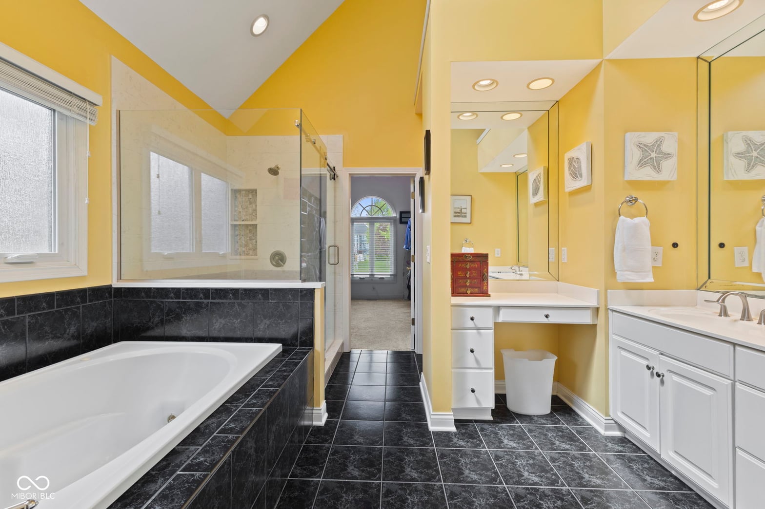 Bright yellow primary bath with soaking tub and shower.