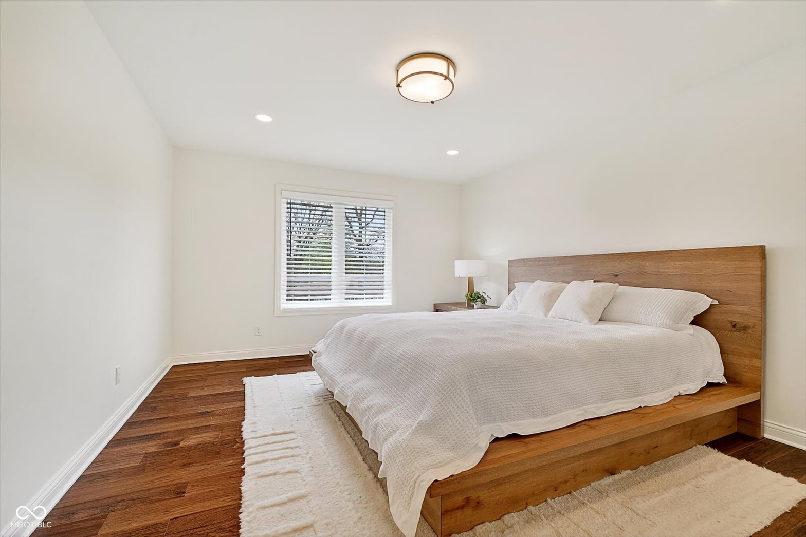Bright primary bedroom with hardwood floors and modern finishes.