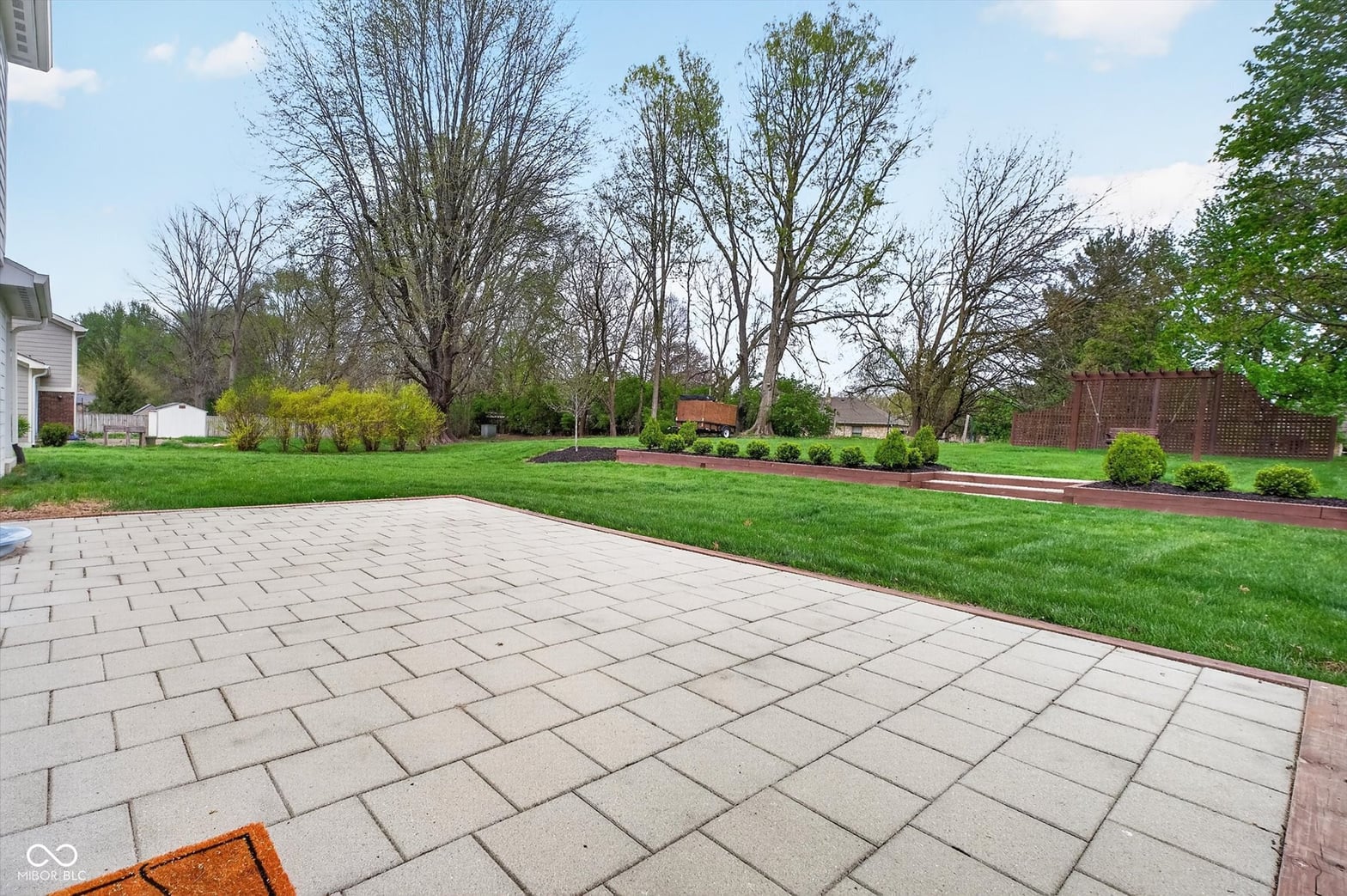 Spacious paver patio with mature landscaping and privacy.