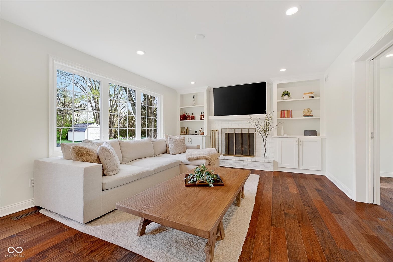 Bright living room with fireplace, built-ins, and hardwood floors.