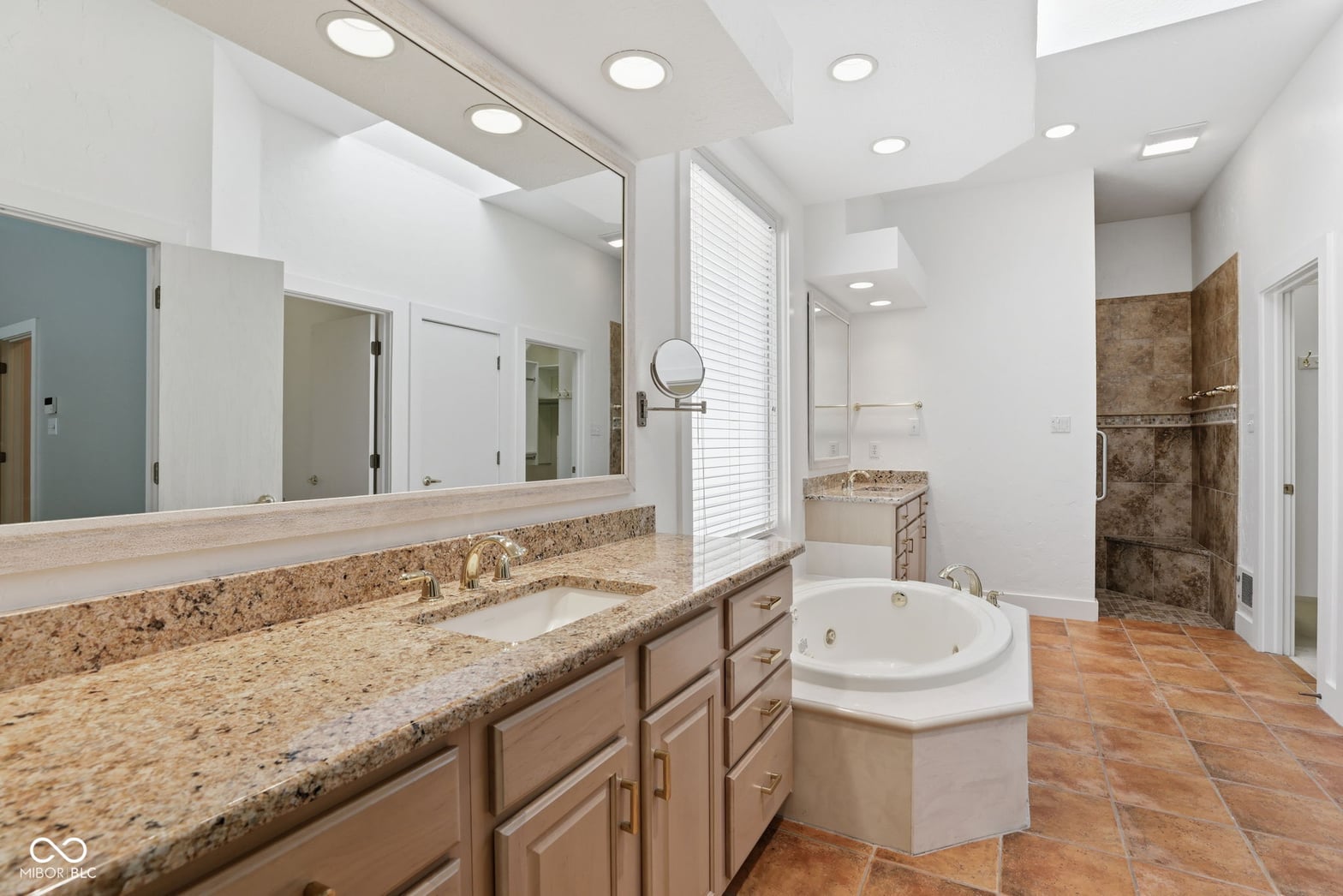 Luxurious primary bath with granite counters and soaking tub.