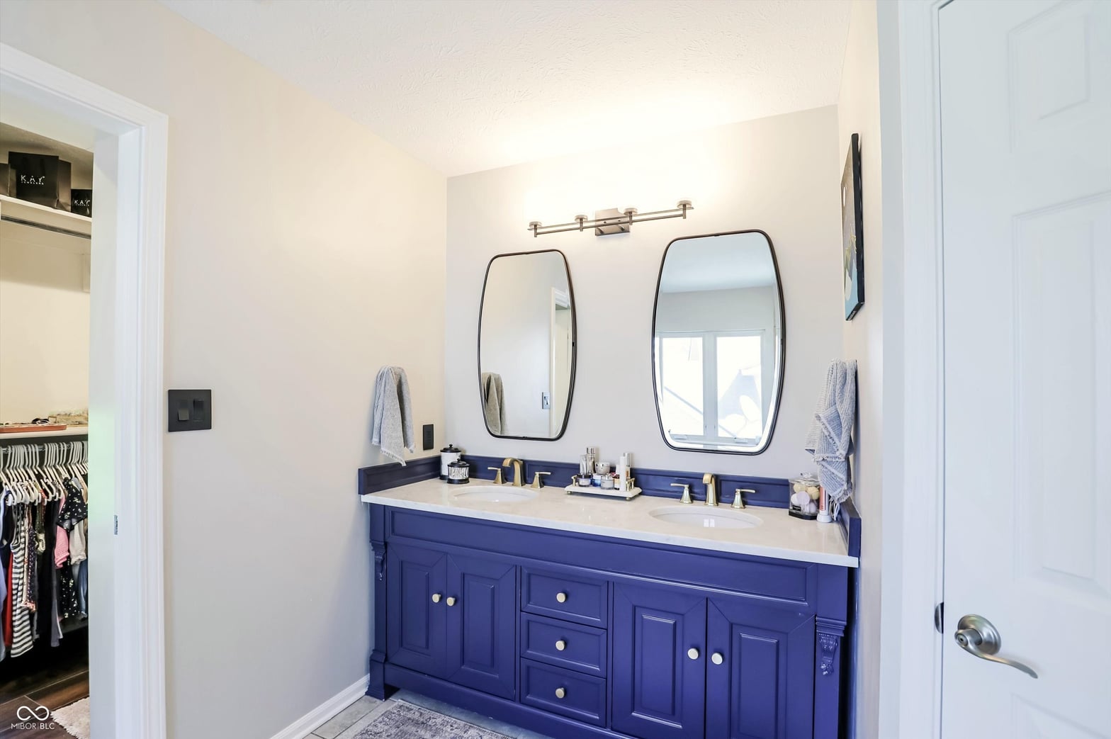 Stunning dual vanity with navy cabinets and brass accents.
