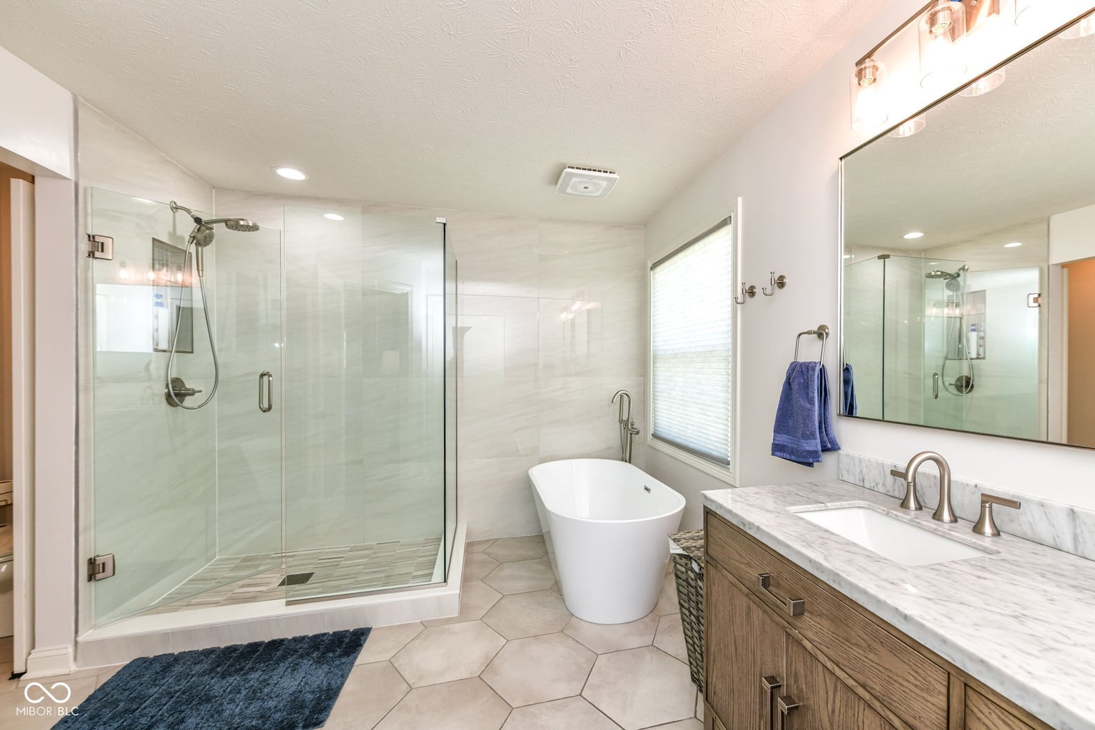 Luxurious primary bath with freestanding tub and frameless shower.