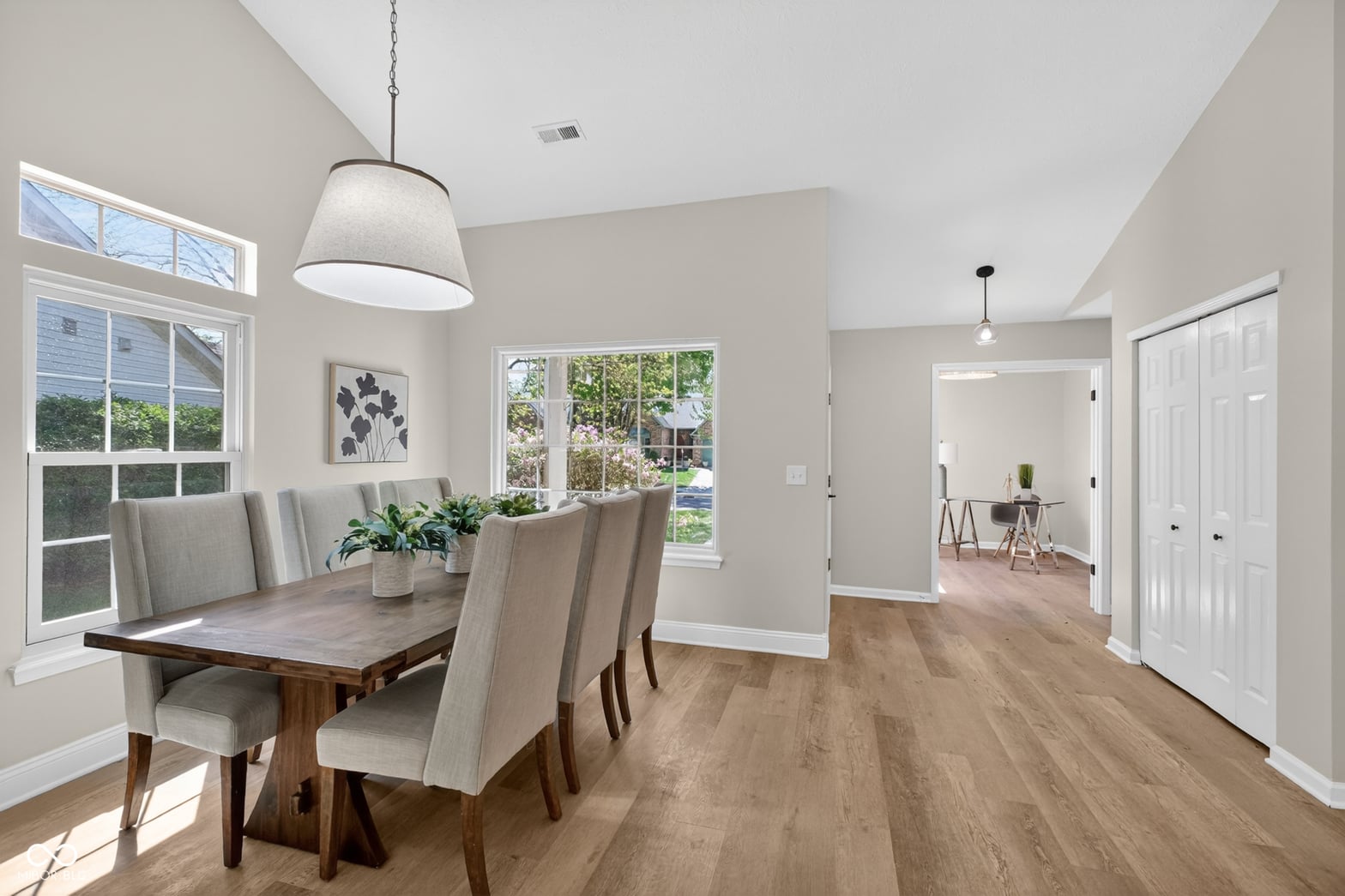 Bright dining room with vaulted ceilings and backyard views.