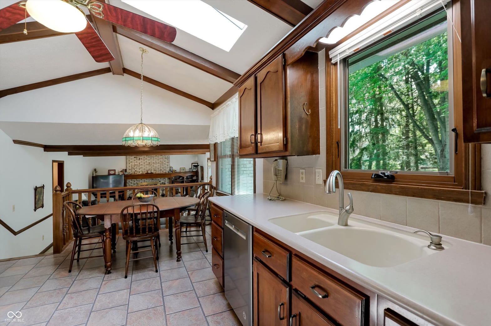 Bright vaulted kitchen with skylights and forest views.