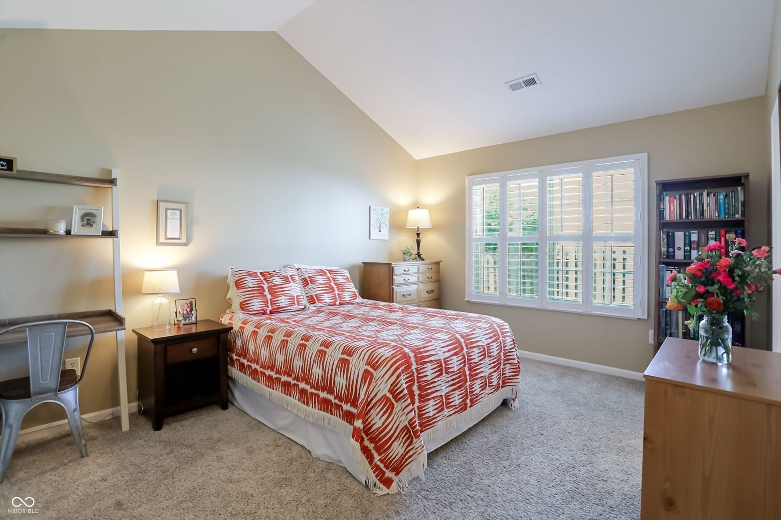 Spacious primary bedroom with plantation shutters and tray ceiling.