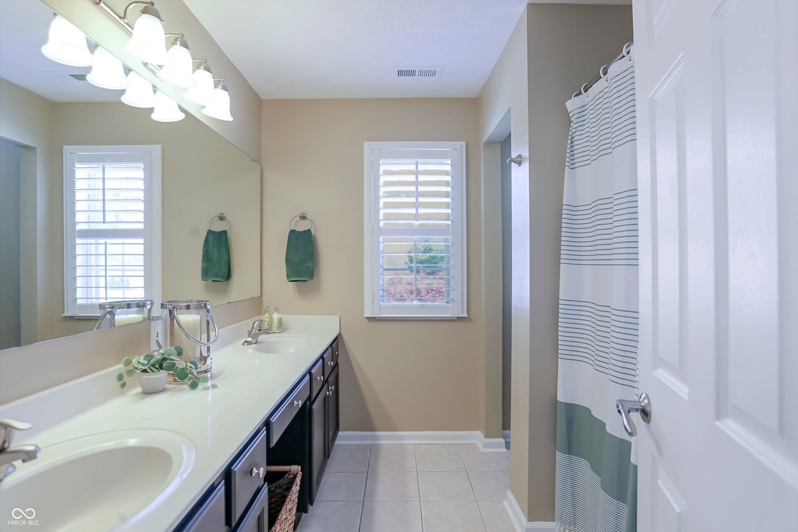 Bright primary bath with dual vanity and soaking tub.